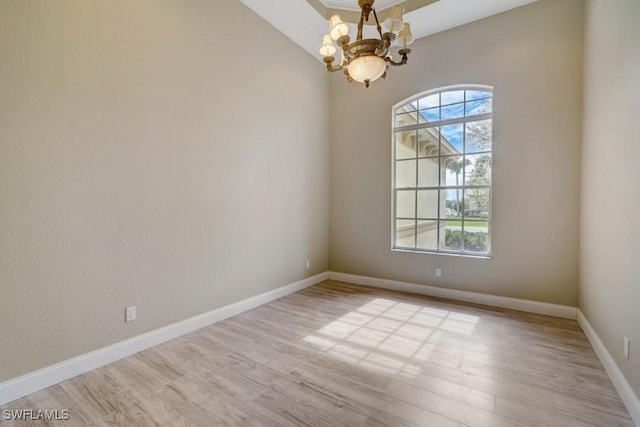 spare room featuring a notable chandelier and light hardwood / wood-style flooring