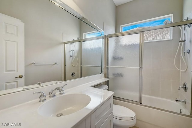 full bathroom with bath / shower combo with glass door, vanity, and toilet