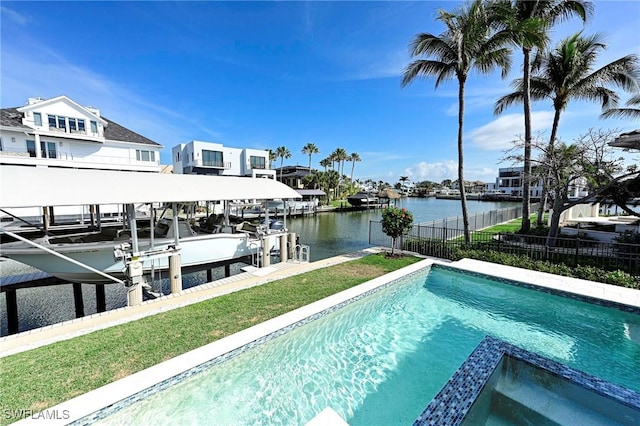 view of swimming pool with boat lift, a pool with connected hot tub, a water view, fence, and a dock