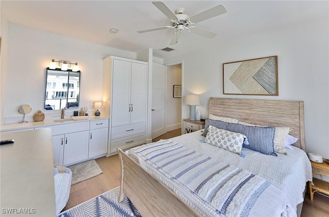 bedroom featuring light wood-style floors, ceiling fan, visible vents, and a sink