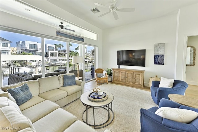 living area with light wood-style floors, visible vents, ceiling fan, and baseboards