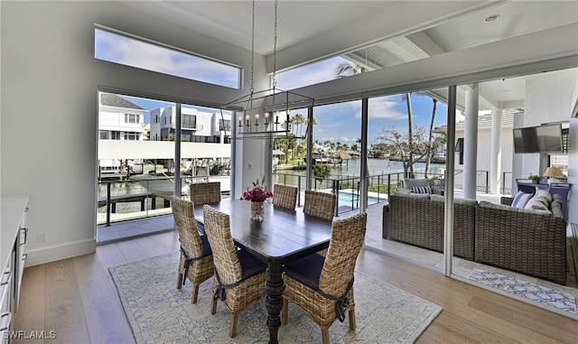 dining area with an inviting chandelier, baseboards, and light wood finished floors