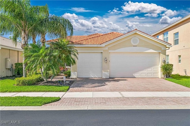 view of front of property with a garage, a tile roof, decorative driveway, and stucco siding