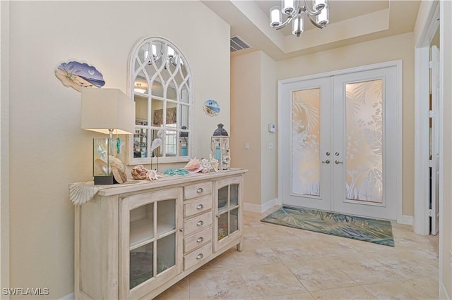 foyer entrance with visible vents, baseboards, french doors, a raised ceiling, and an inviting chandelier