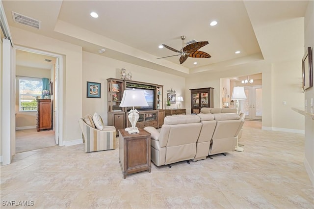 living area featuring a tray ceiling, visible vents, baseboards, and recessed lighting