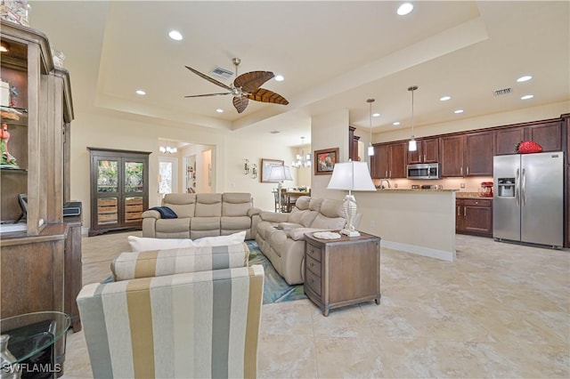 living area featuring a ceiling fan, a raised ceiling, visible vents, and recessed lighting