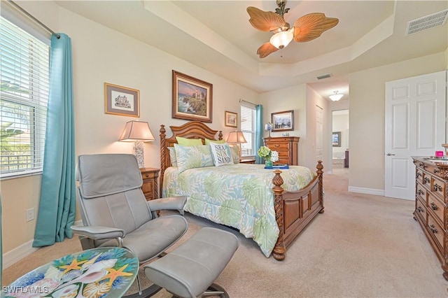 bedroom featuring multiple windows, visible vents, and a raised ceiling