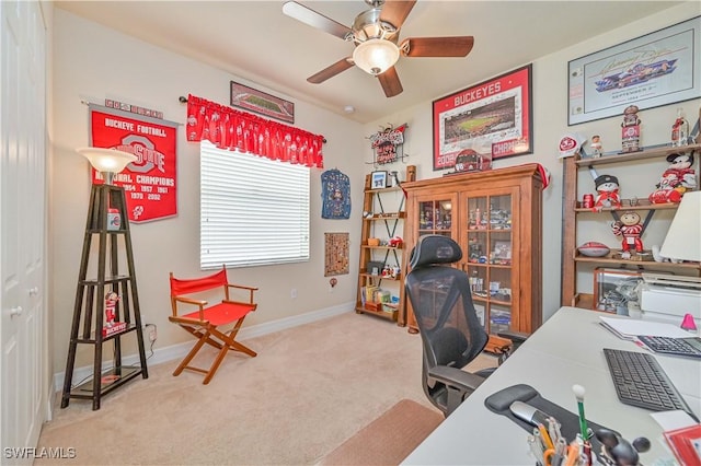 carpeted office space with ceiling fan and baseboards