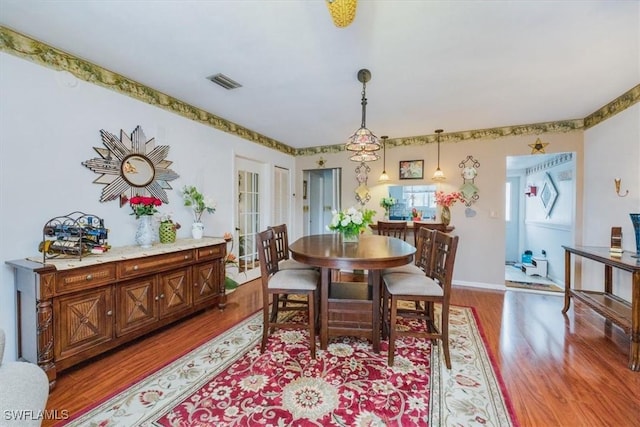 dining area with wood finished floors, visible vents, and baseboards