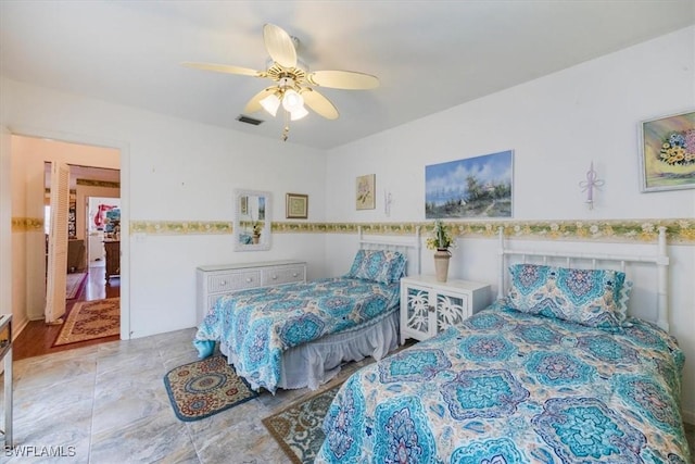 bedroom featuring a ceiling fan, a wainscoted wall, and visible vents