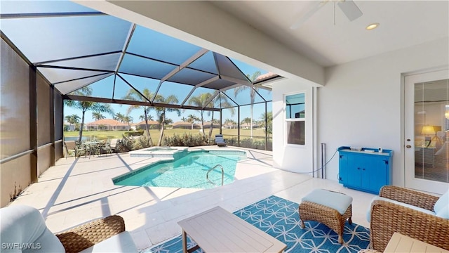 view of pool with a ceiling fan, glass enclosure, a pool with connected hot tub, and a patio area