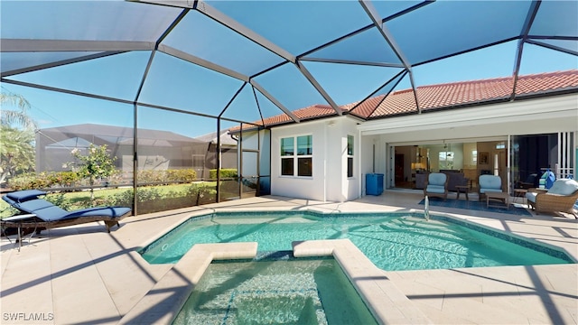 view of pool featuring glass enclosure, a pool with connected hot tub, and a patio