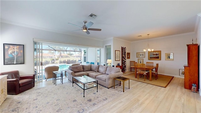 living area featuring light wood-style flooring, ceiling fan with notable chandelier, visible vents, and ornamental molding