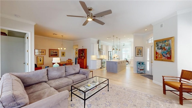 living area with recessed lighting, ceiling fan with notable chandelier, baseboards, light wood-type flooring, and crown molding