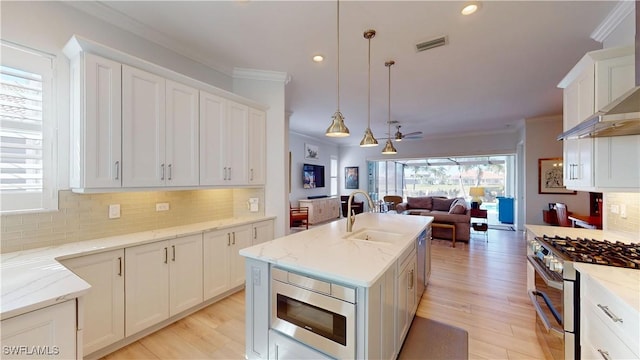 kitchen with stainless steel appliances, visible vents, ornamental molding, open floor plan, and a sink