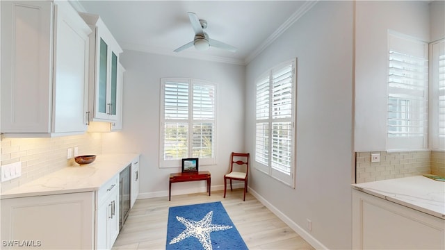 living area featuring ornamental molding, ceiling fan, light wood-style flooring, and baseboards