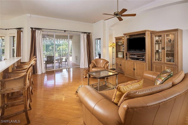 living area with light wood-type flooring, ornamental molding, and a ceiling fan