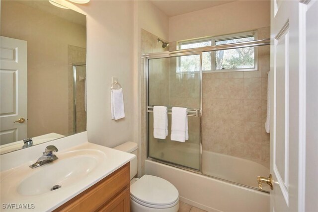 bathroom with bath / shower combo with glass door, toilet, and vanity