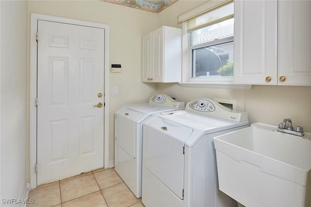 laundry area with cabinet space, independent washer and dryer, a sink, and light tile patterned floors