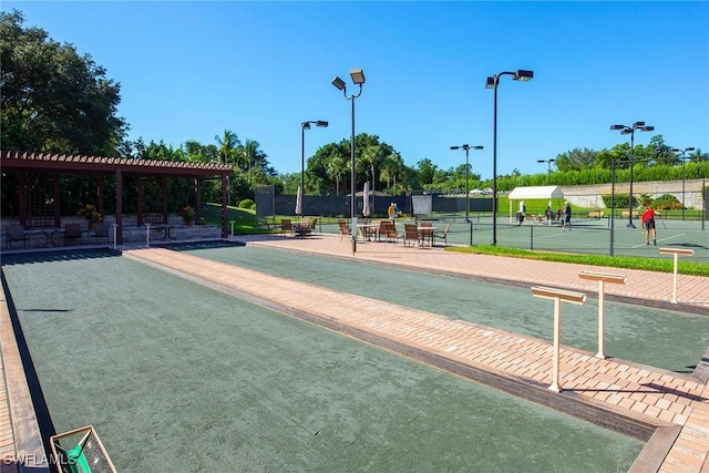 view of property's community with a tennis court and fence