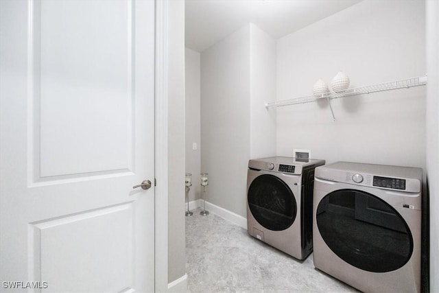 washroom with laundry area, baseboards, and washer and clothes dryer