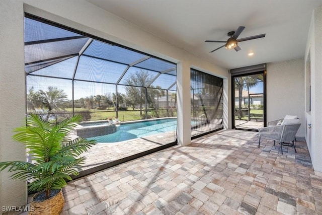 view of pool with a patio area, a pool with connected hot tub, glass enclosure, and a ceiling fan