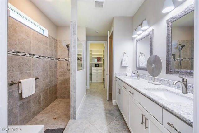 full bathroom with visible vents, a sink, a spacious closet, and a walk in shower