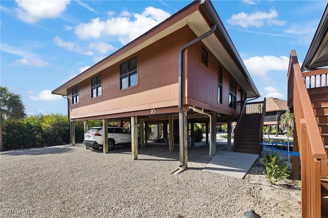 exterior space featuring gravel driveway, stairway, and a carport