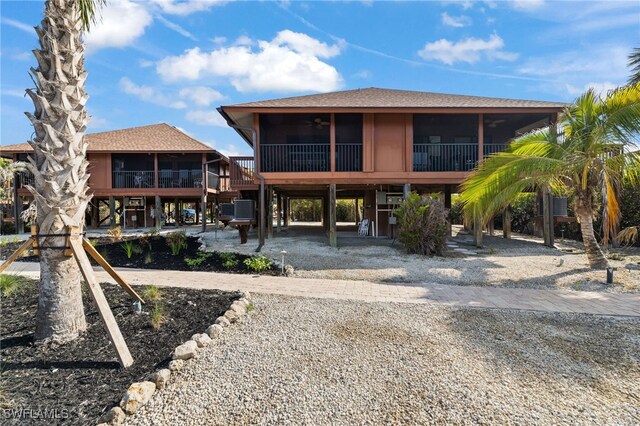 1811 Olde Middle Gulf Dr Unit 10, Sanibel, FL 33957 - rear view of house featuring a shingled roof, a sunroom, driveway, and a carport