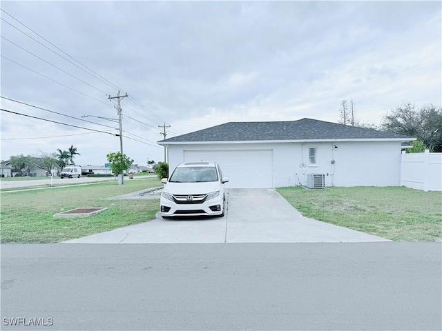 ranch-style home featuring an attached garage, driveway, a front yard, and cooling unit