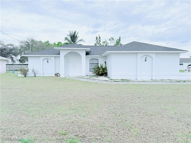 ranch-style house featuring a front lawn, roof with shingles, and stucco siding