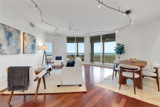 living room with expansive windows, rail lighting, and light hardwood / wood-style floors