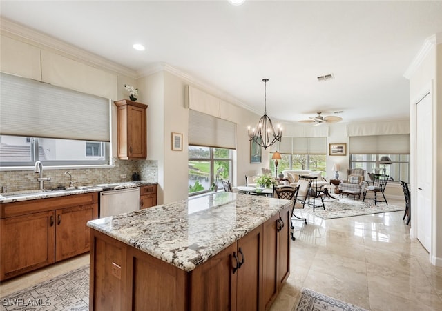 kitchen with a kitchen island, hanging light fixtures, ornamental molding, stainless steel dishwasher, and brown cabinetry