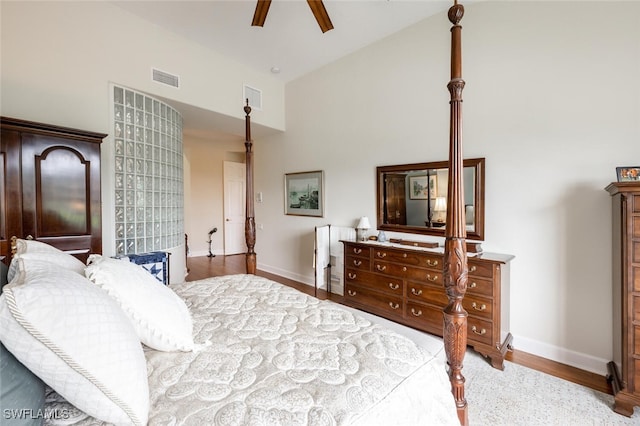 bedroom featuring high vaulted ceiling, visible vents, light wood-style flooring, and baseboards