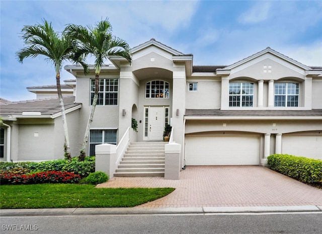 view of front facade with an attached garage, decorative driveway, and stucco siding