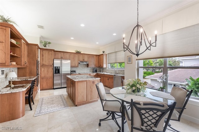 kitchen featuring light stone counters, pendant lighting, visible vents, appliances with stainless steel finishes, and a sink