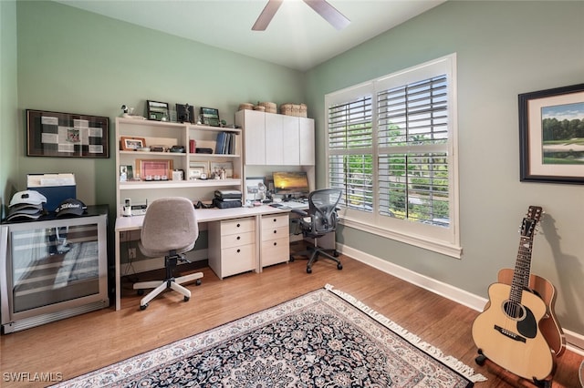 home office with light wood-style floors, baseboards, and a ceiling fan