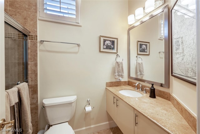 full bathroom featuring baseboards, a tile shower, vanity, and toilet