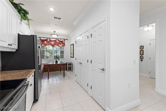 kitchen featuring visible vents, stainless steel electric stove, ornamental molding, light tile patterned floors, and white cabinetry