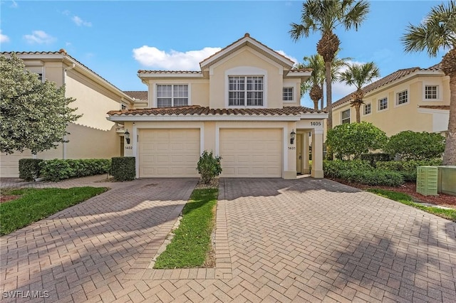 mediterranean / spanish house with a garage, decorative driveway, a tile roof, and stucco siding