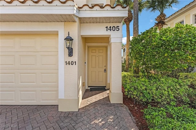 view of exterior entry featuring a garage and stucco siding