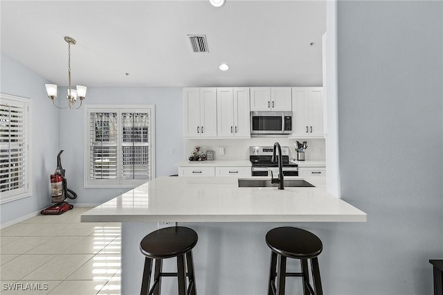 kitchen with appliances with stainless steel finishes, visible vents, a sink, and a kitchen breakfast bar