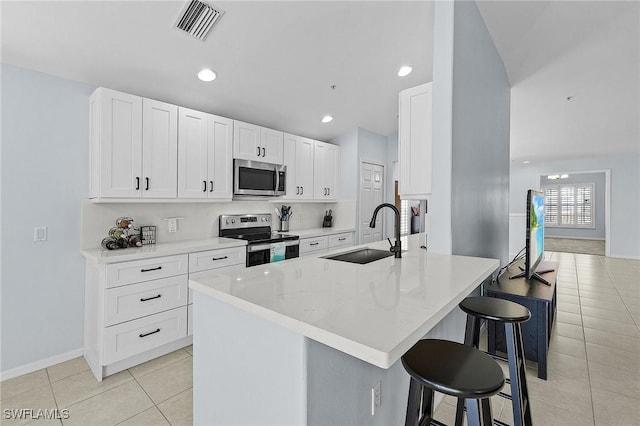 kitchen featuring a breakfast bar area, visible vents, appliances with stainless steel finishes, light tile patterned flooring, and a sink