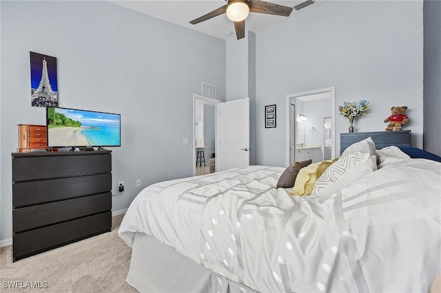 carpeted bedroom with visible vents, baseboards, a towering ceiling, ensuite bath, and ceiling fan