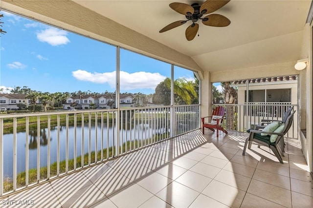 sunroom with lofted ceiling, a water view, a residential view, and ceiling fan