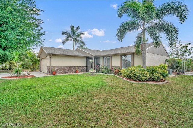 ranch-style home featuring an attached garage, a front yard, cooling unit, and stucco siding