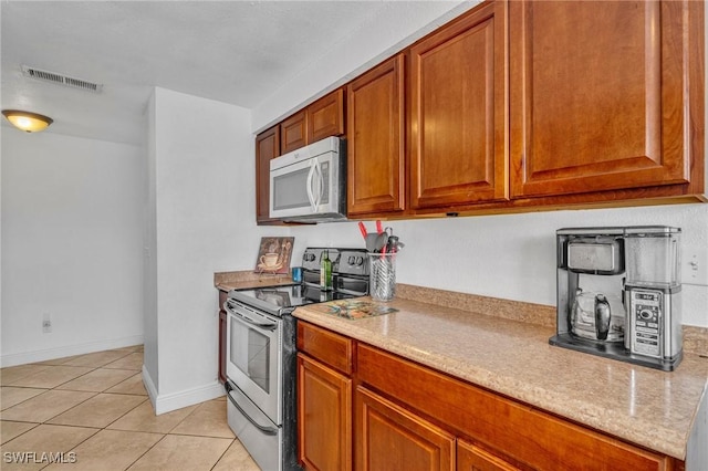 kitchen featuring appliances with stainless steel finishes, light tile patterned flooring, visible vents, and brown cabinets