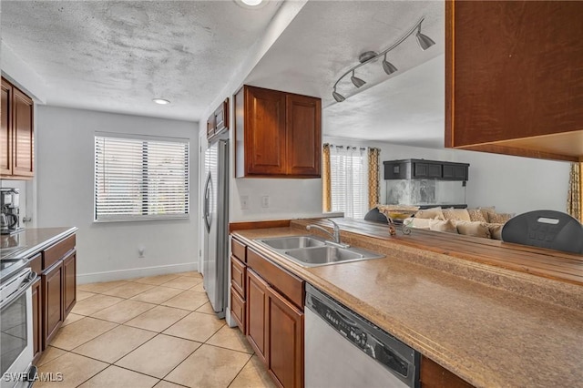 kitchen with a healthy amount of sunlight, a textured ceiling, stainless steel appliances, and a sink