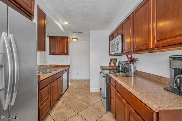 kitchen with light tile patterned floors, stainless steel appliances, light countertops, visible vents, and a sink