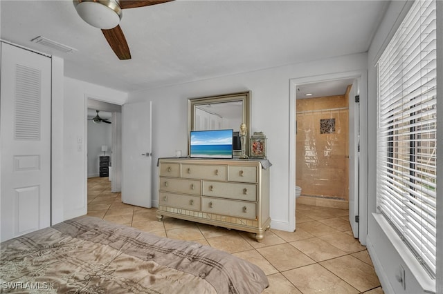 bedroom with light tile patterned floors, ensuite bath, visible vents, and a ceiling fan